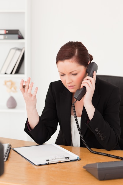 Infuriata bella donna dai capelli rossi in tuta telefonando