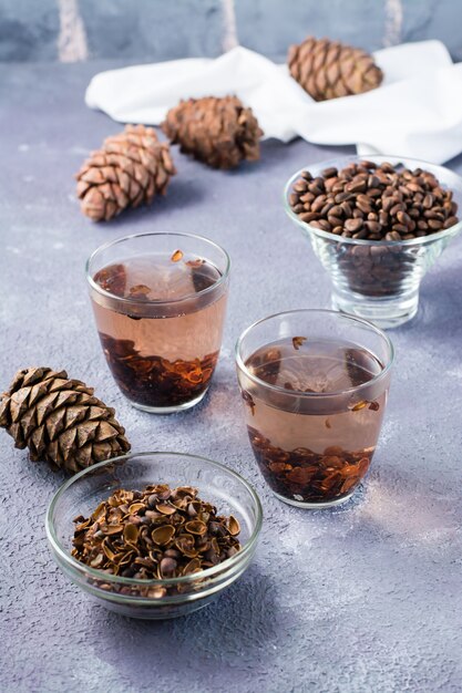 Infuso di gusci di pinoli in bicchieri e pinoli sul tavolo. Medicina alternativa. Vista verticale