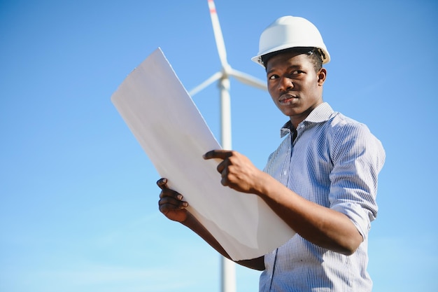 Ingegnere africano in piedi con turbina eolica