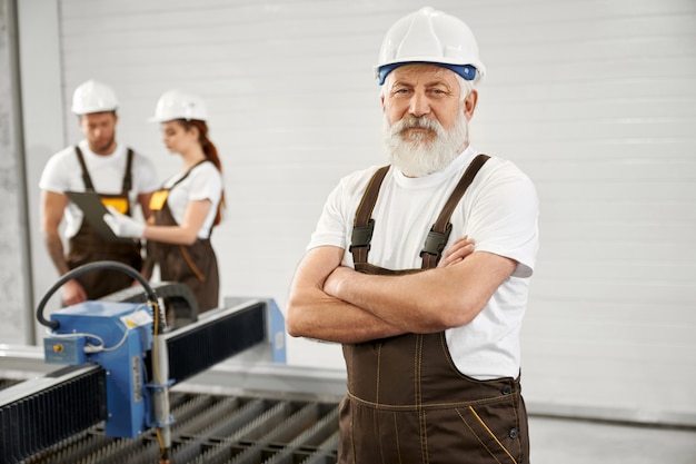 Ingegnere anziano che posa sulla fabbrica di lavorazione dei metalli.