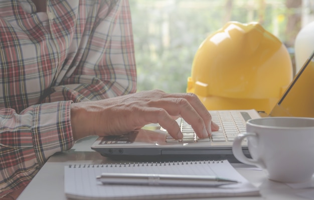 Ingegnere architetto con laptop per lavorare con casco giallo