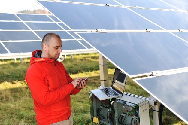 Ingegnere che lavora con laptop da pannelli solari, parlando al cellulare