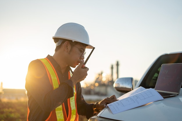 Ingegnere che lavora con un computer portatile e parla con un walkie-talkie in cantiere