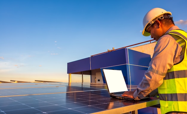 ingegnere che utilizza laptop a pannelli solari sul tetto al tramonto ingegnere che lavora in un impianto fotovoltaico