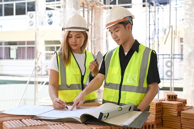 Ingegnere civile e specialisti che lavorano insieme al piano di controllo in cantiere Concetto di costruzione dell'ingegnere industriale