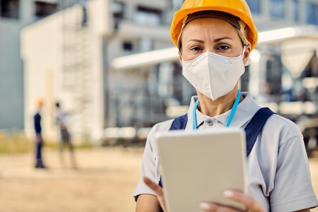 Ingegnere civile femminile che indossa una maschera protettiva durante l'utilizzo del touchpad in cantiere