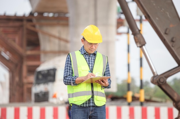 Ingegnere con la lista di controllo del blocco sul cantiere di infrastrutture Foreman in cappello