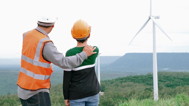 Ingegnere con suo figlio in un parco eolico in cima a una collina o a una montagna rurale Ideale progressista per la futura produzione di energia rinnovabile sostenibile Generazione di energia da turbina eolica