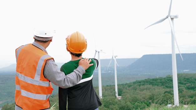 Ingegnere con suo figlio in un parco eolico in cima a una collina o montagna nelle zone rurali Progressivo ideale per la futura produzione di energia rinnovabile sostenibile Generazione di energia dalla turbina eolica