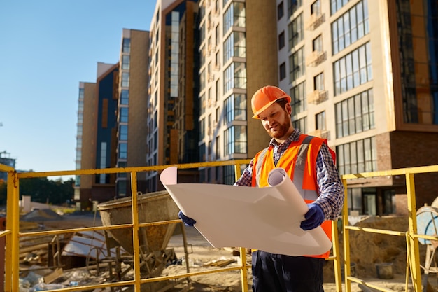 Ingegnere costruttore azienda progetto in piedi fuori sopra il cantiere con edifici incompiuti