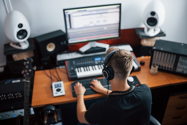 Ingegnere del suono in cuffia che lavora e mixa musica all'interno dello studio.
