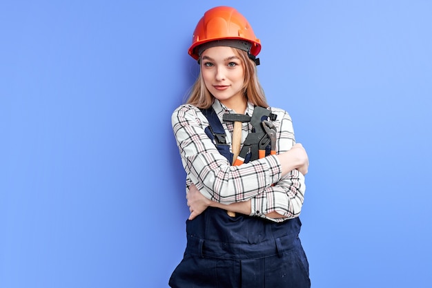 Ingegnere donna che indossa casco arancione e tuta blu che tiene gli strumenti