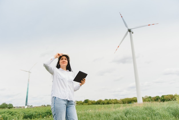 Ingegnere donna con elmetto al parco di turbine eoliche