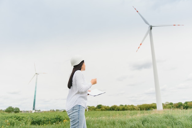 Ingegnere donna con elmetto al parco di turbine eoliche