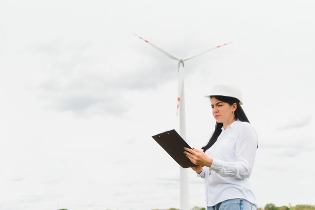 Ingegnere donna con elmetto che lavora presso l'impianto di turbine eoliche