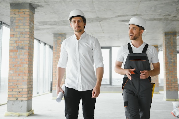 Ingegnere e lavoratore che controllano il progetto nel cantiere edile sfondo cantiere al tramonto in serata