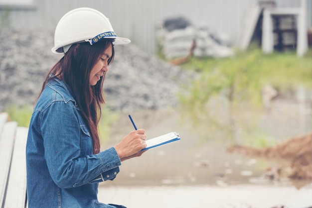 Ingegnere edile donna indossare elmetto bianco di sicurezza al lavoratore dell'industria del cantiere Ingegnere femminile lavoratore ingegneria civile con casco di sicurezza elmetto Donna ingegnere edile concetto