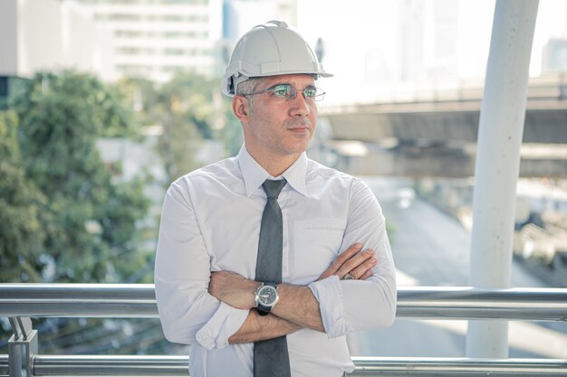 Ingegnere edile fiducioso in cappello duro guardando i progetti di costruzione.