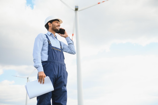 Ingegnere indiano durante l'attività di un mulino a vento per generare elettricità Uomo asiatico che lavora in un parco di turbine eoliche Energia pulita e verde