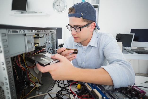 Ingegnere informatico sorridente che lavora alla console rotta con il cacciavite