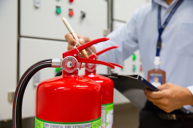 Ingegnere ispezione Estintore nella sala controllo incendi.