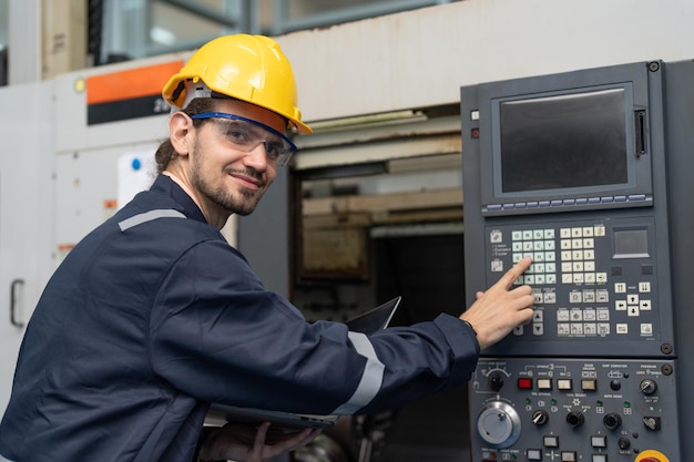 Ingegnere maschio che aziona macchina cnc nel pannello di controllo in fabbrica