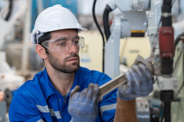 Ingegnere maschio che utilizza la saldatrice del braccio del robot di riparazione dello strumento della chiave inglese in fabbrica