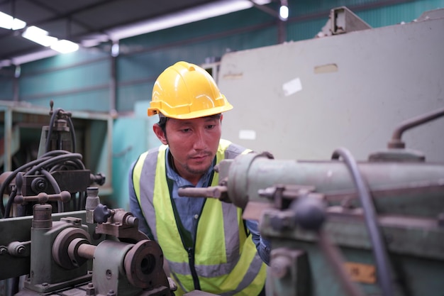 Ingegnere maschio metalmeccanico operatore industriale esperto tecnico lavoratore in casco rigido di sicurezza che lavora su tornio, uomo professionista nell'officina della fabbrica di produzione di tecnologia industriale