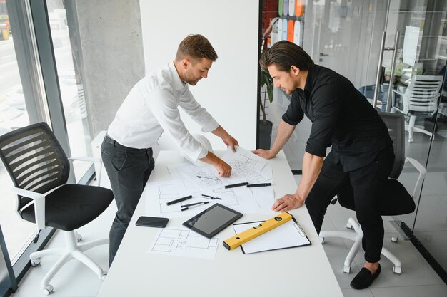 Ingegnere o architetto lavoro di squadra che lavora su un progetto di costruzione con modello di edificio e progetto in ufficio Concetto di costruzione