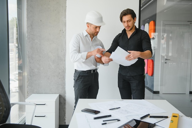 Ingegnere o architetto lavoro di squadra che lavora su un progetto di costruzione con modello di edificio e progetto in ufficio Concetto di costruzione