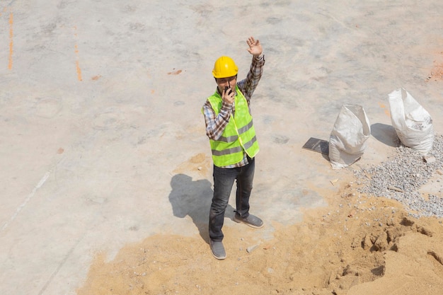 Ingegnere o architetto maschio asiatico professionista che tiene walkietalkie che lavora in un cantiere