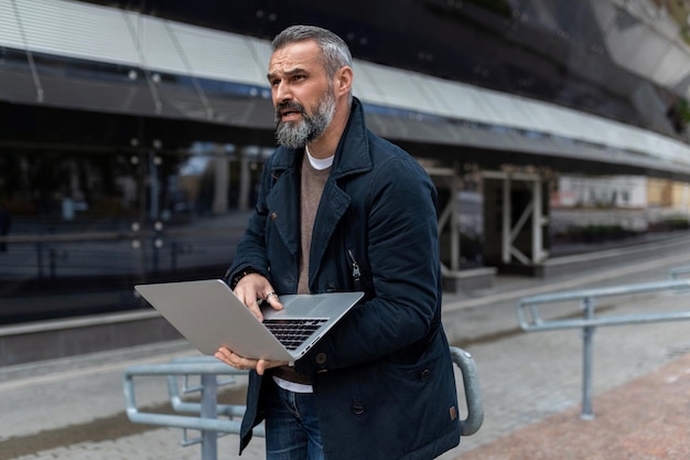 Ingegnere software per adulti con un laptop in mano sullo sfondo di un business center per ufficio