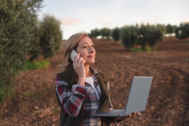 Ingegnere sul campo femminile con un computer portatile che esamina la piantagione agricola