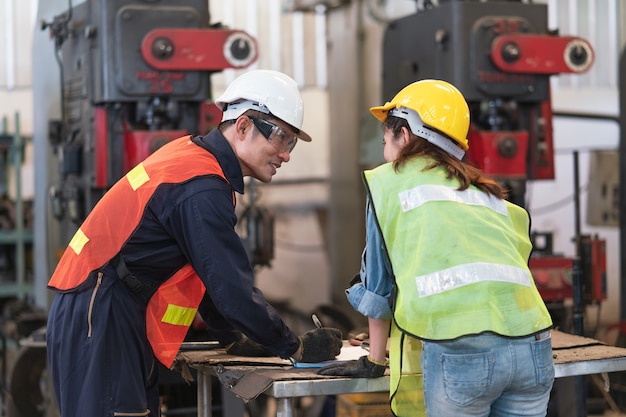 Ingegnere uomo asiatico che spiega macchina di ispezione ingegnere femminile in linea di produzione in una fabbrica industriale