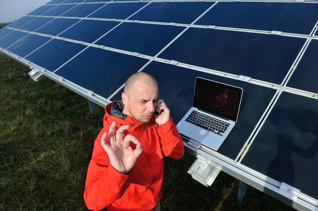 ingegnere uomo d'affari che utilizza il computer portatile al campo di energia eco dell'impianto di pannelli solari in background