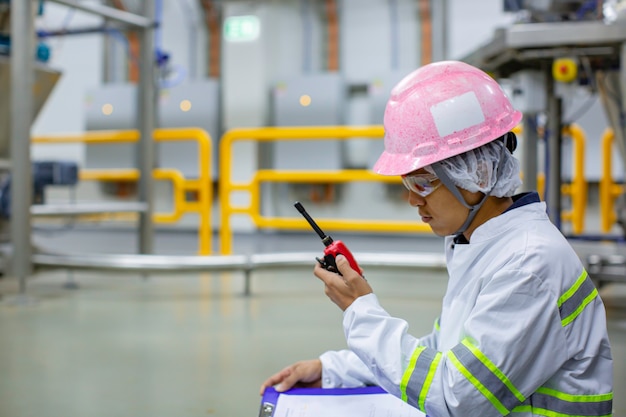 Ingegneri maschi protezione del suono e personale uniforme. Ricetrasmettitore radio portatile per la comunicazione del lavoro di ispezione della cantina in polvere presso la fabbrica di serbatoi verticali in acciaio inossidabile