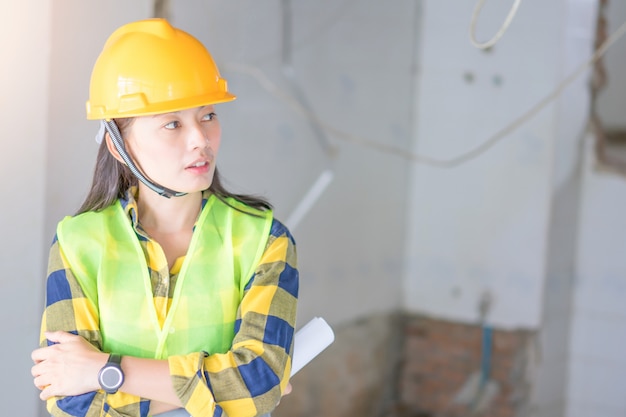 Ingegneria delle donne che indossa casco giallo e che lavora al cantiere