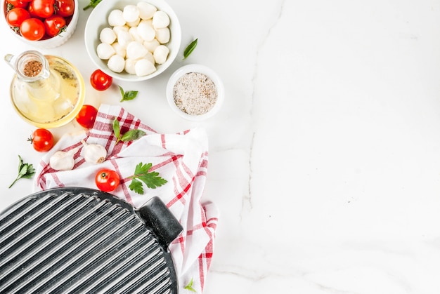 Ingrediente alimentare italiano della pizza casalinga della pasta sulla tavola di marmo bianca con la vista superiore degli accessori della farina, dell'olio d'oliva, del basilico, dei pomodori e della cucina