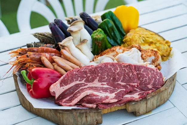 Ingredienti barbecue con verdure e carne allineati sul tavolo all'aperto