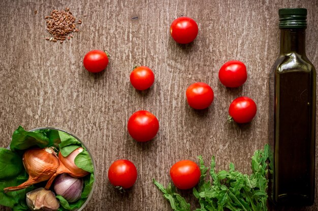 Ingredienti biologici freschi per la produzione di insalata: spinaci, pomodori, germogli, basilico, olio d'oliva su fondo rustico, vista dall'alto. Lay piatto con posto per il testo. Concetto di cibo vegano e sano