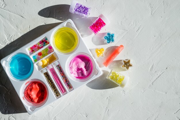 Ingredienti, bottiglie, barattoli per realizzare un popolare giocattolo per bambini con la colla. slime.hobby alla moda