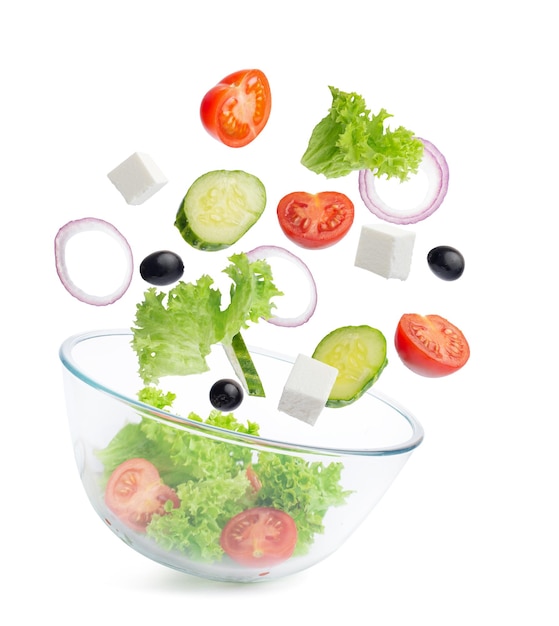 Ingredienti dell'insalata greca che cadono in un'insalatiera di vetro trasparente