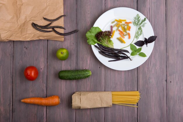 Ingredienti della pasta fresca in sacchetti di carta ecologici spaghetti pasta carota basilico pomodoro e altre verdure