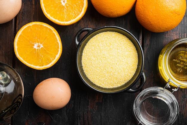 Ingredienti della torta di polenta all'arancia, con uova e miele, su un vecchio fondo di legno scuro, vista dall'alto piatta