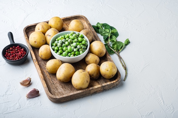 Ingredienti di purè di patate con piselli e menta, sul tavolo bianco