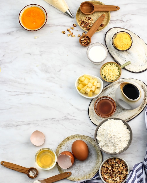 Ingredienti e strumenti di cottura su fondo di marmo luminoso d'avanguardia. Farina, uova, zucchero, latte, burro, layout, flatlay, vista dall'alto, spazio di copia