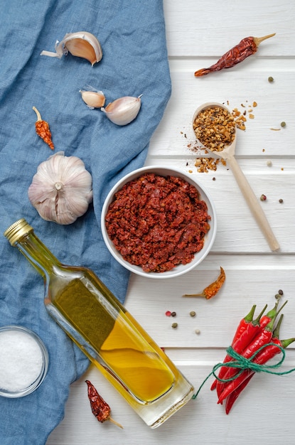 Ingredienti Harissa per la cottura di peperoncino piccante, sale marino grosso, aglio, cumino zira, olio d'oliva, coriandolo macinato su un tavolo di ardesia scuro. adjika, muhammara. Cucina orientale.