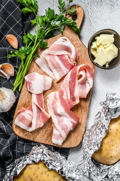 Ingredienti per cucinare patate al forno con pancetta, burro, prezzemolo e formaggio