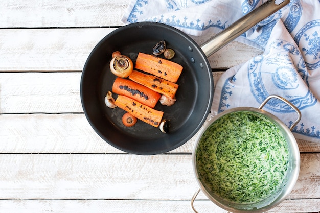 Ingredienti per cucinare Zuppa di spinaci con carote e crostini in una ciotola su un tavolo di legno