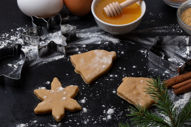 Ingredienti per fare i biscotti di pan di zenzero di Natale: uova, farina, miele, cannella, zenzero su fondo nero